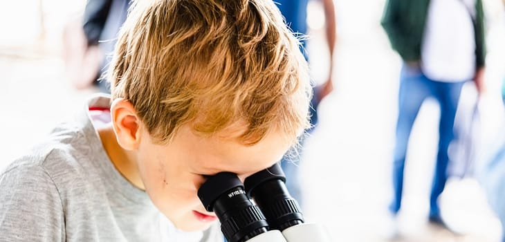 Child with curiosity during a medicine fair looking at bacteria