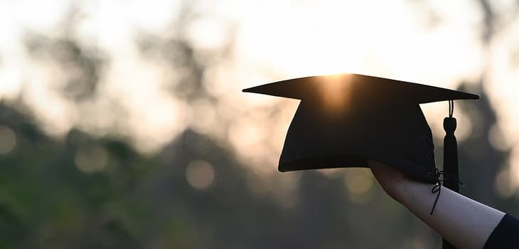 Cropped image of university student hand holding a graduation hat.