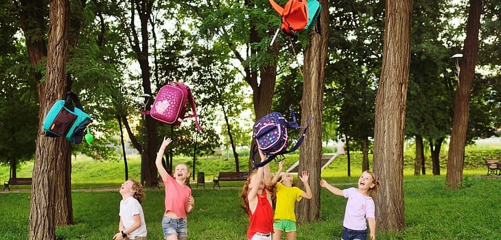 group of school children rejoice at the beginning of the summer holidays, throw up their school